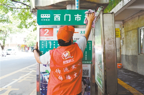 志愿者在认真擦拭公交站牌,希望它每天都以一尘不染的容貌迎接市民。特约摄影师 志愿者在认真擦拭公交站牌,希望它每天都以一尘不染的容貌迎接市民。特约摄影师